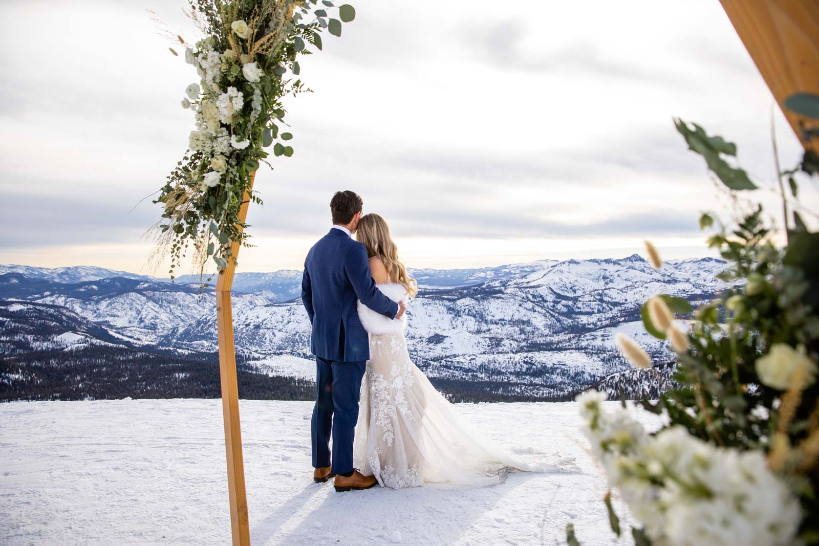 Bride and groom embrace on Mammoth Mountain with the Eastern Sierra mountains
