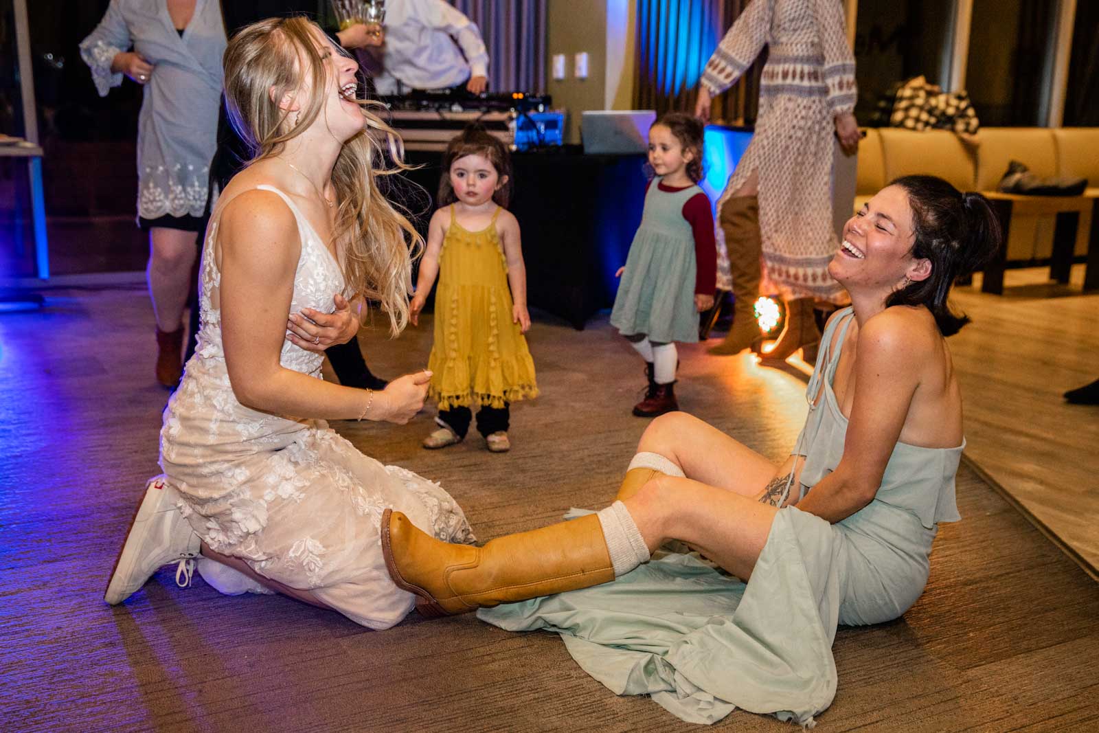 Bride laughs on floor dancing with friends