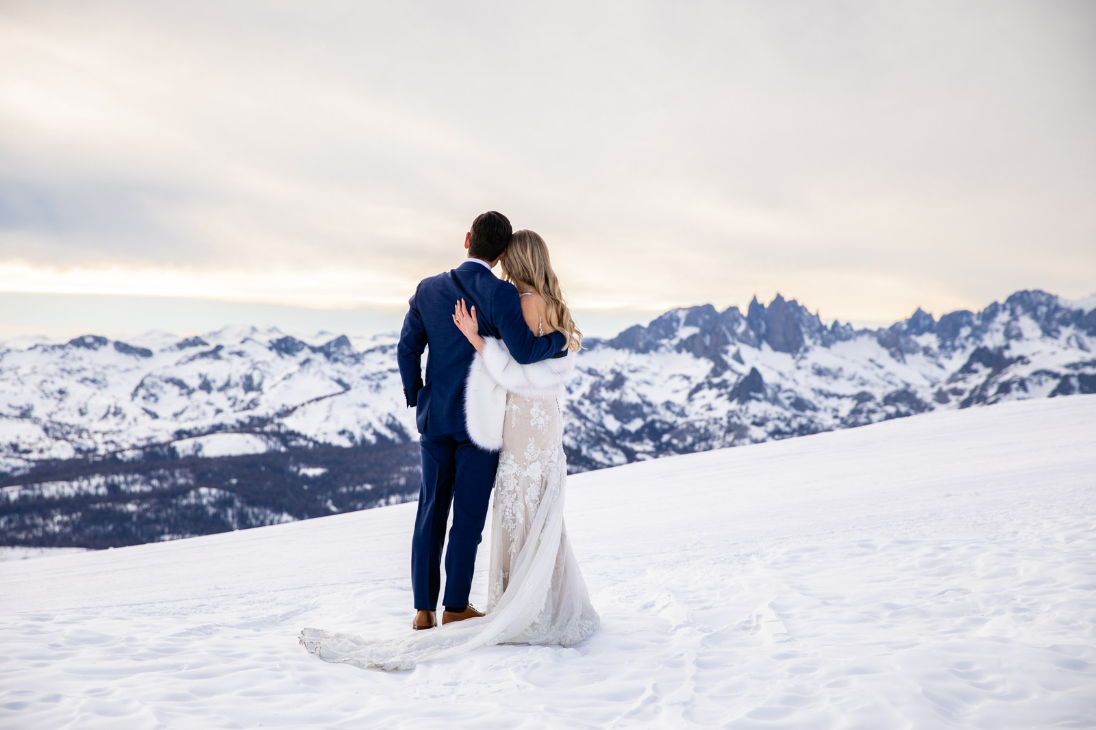 Bride and groom embrace on Mammoth Mountain with the Minaret mountains