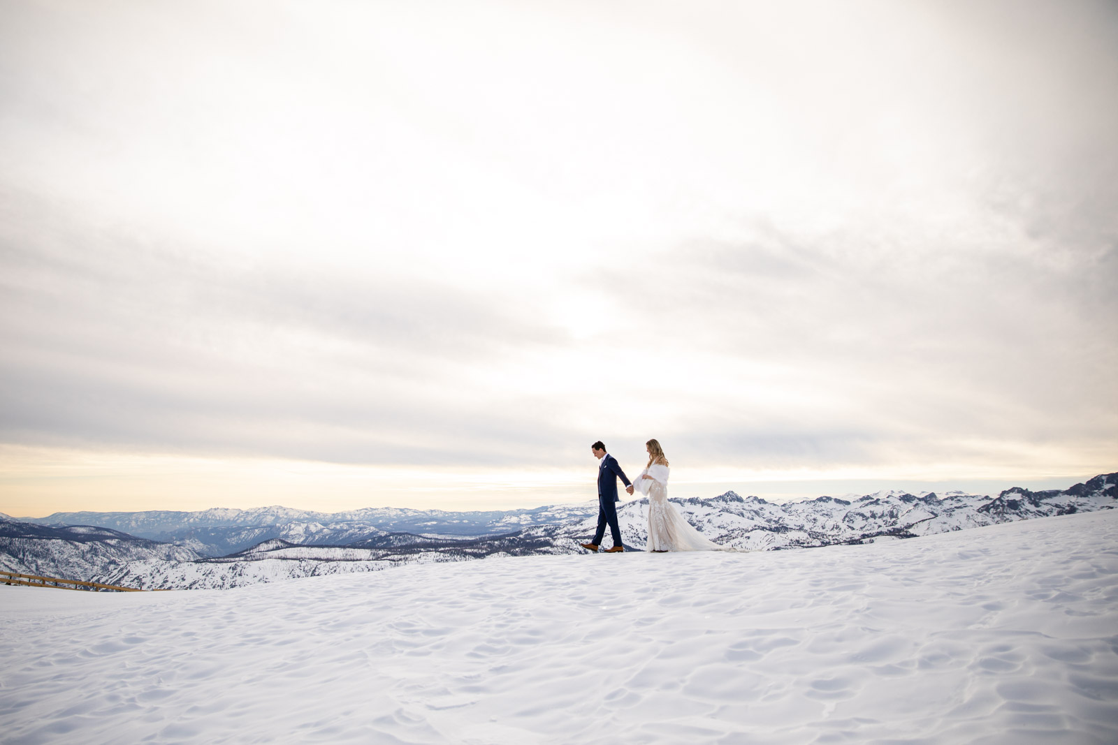 Bride and groom walk on Mammoth Mountain with the Eastern Sierra mountains
